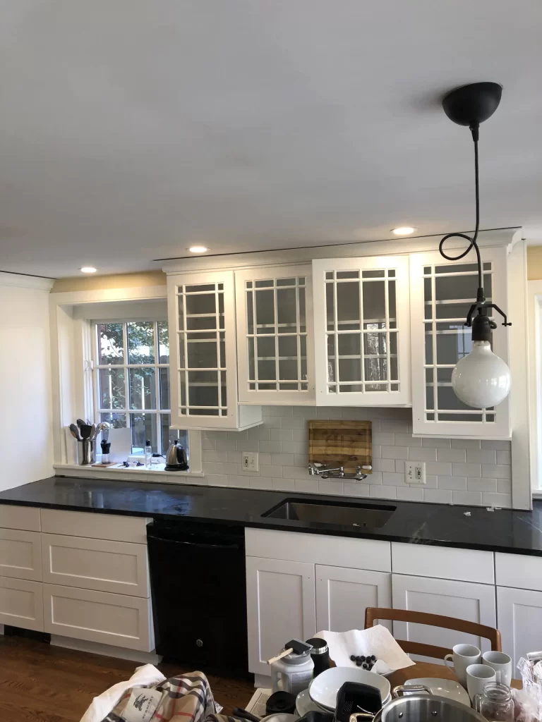 Interior painting services in Austin, Texas kitchen with white cabinets, modern lighting, and fresh painted finishes.